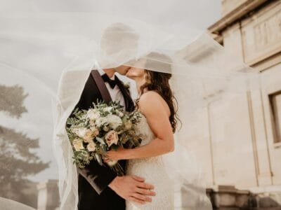 Bride and groom share a tender kiss under a veil, showcasing love and romance on their special day.