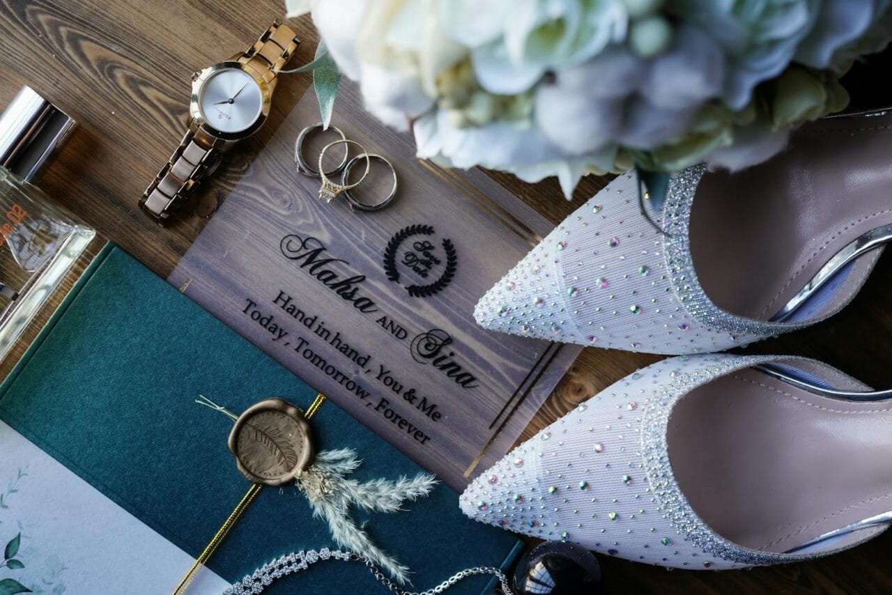 Stylish wedding flat lay featuring jewelry, shoes, and a decorative wedding invitation.