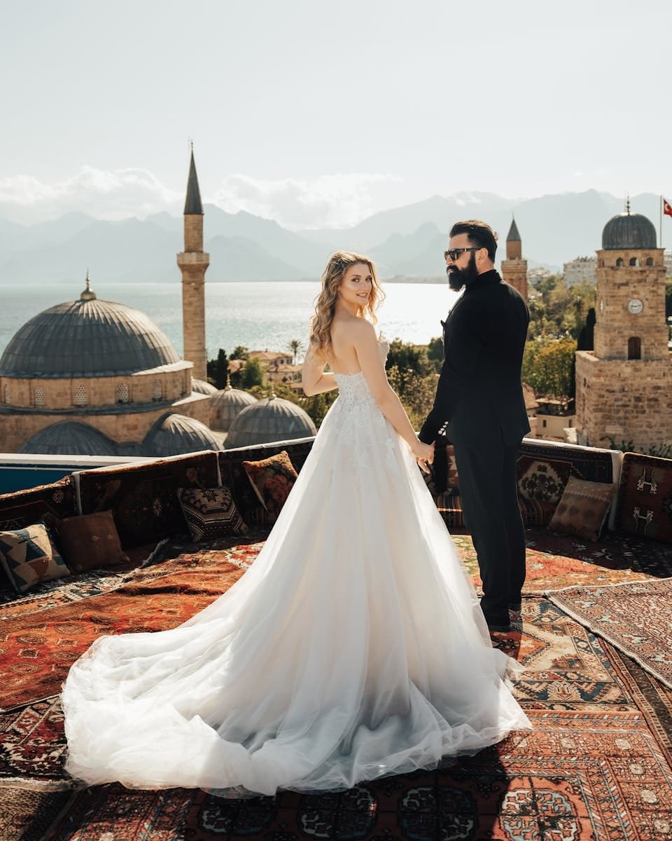 Bride and groom on a rooftop with a panoramic view of domes and mountains.