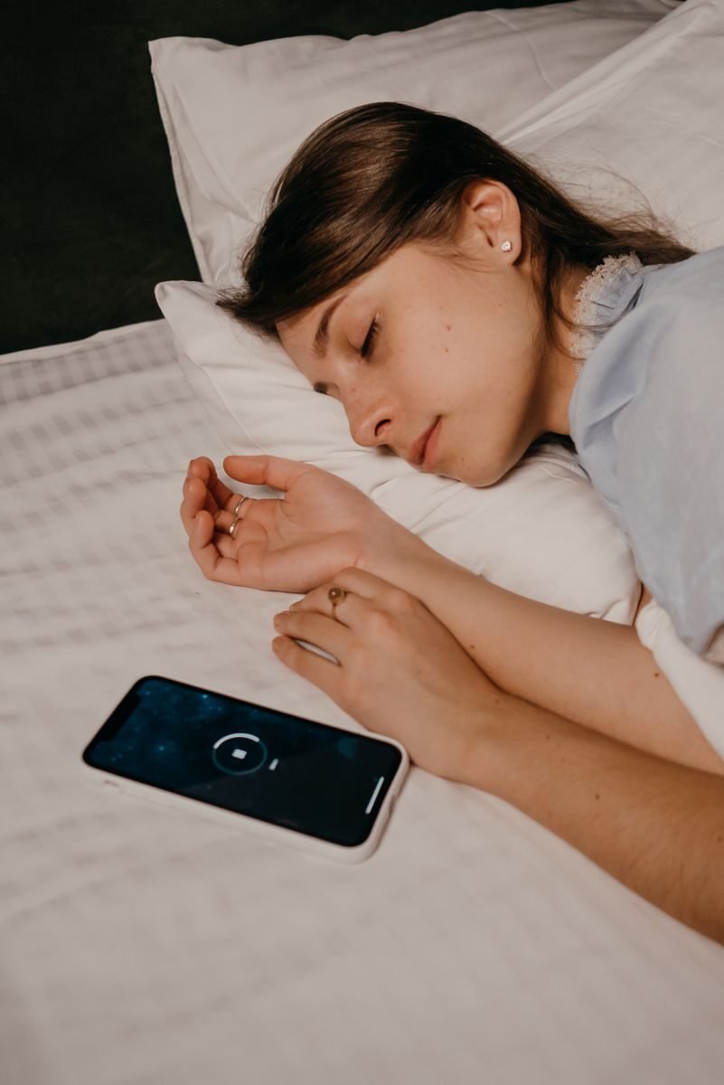 A woman sleeping peacefully with a smartphone on the bed, conveying a calm and restful night.