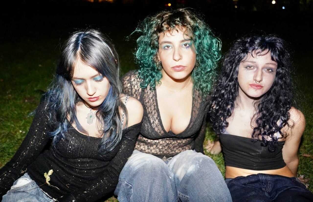 Three young women with colorful hair posing outdoors