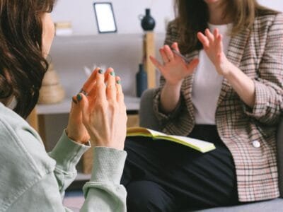 Two women engaged in a therapy session, communication and support in an office setting.