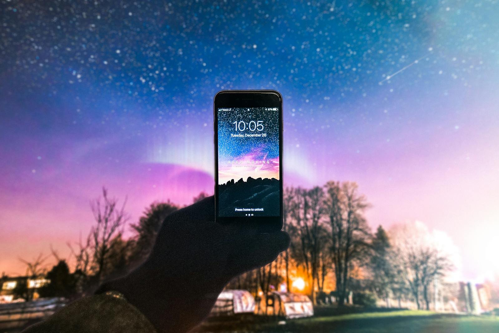 A smartphone displaying the night sky held against a beautiful starry backdrop in Vilnius, Lithuania.