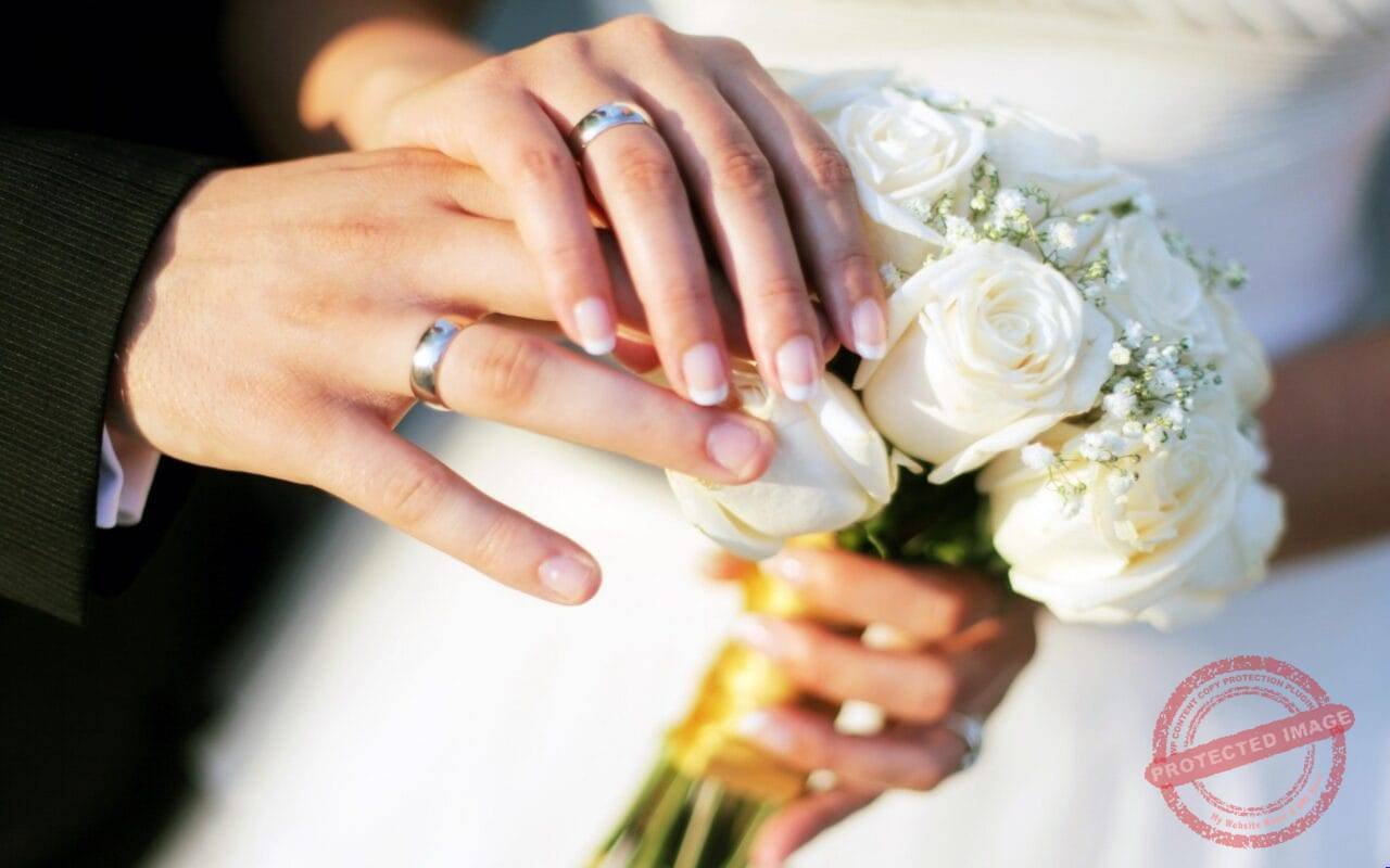 Hands wedding rings bouquet roses