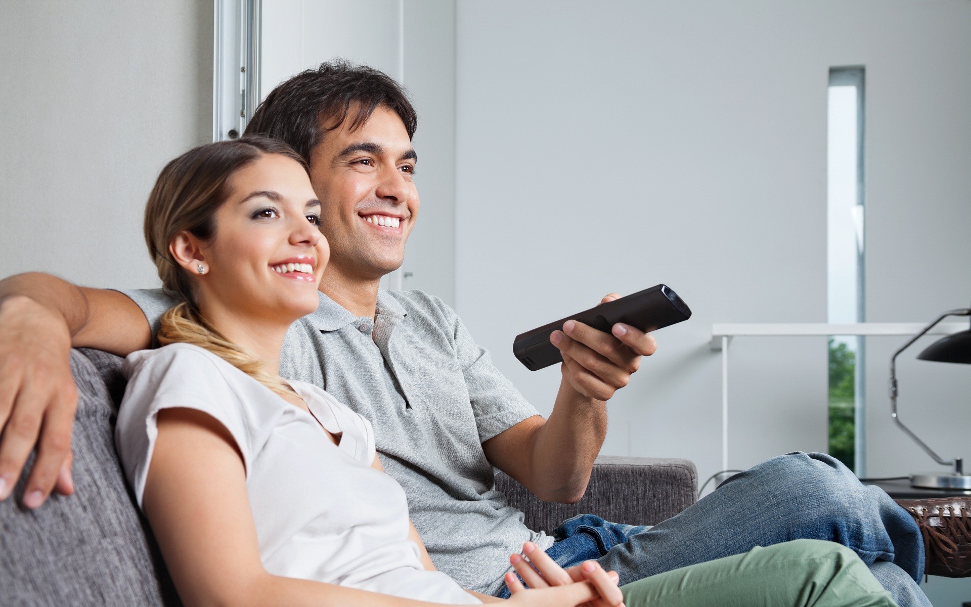 Happy couple watching TV Straipsniai.lt