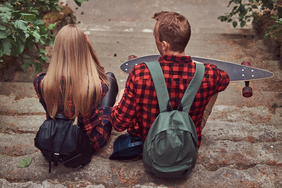 back view young hipster couple sitting steps park Straipsniai.lt