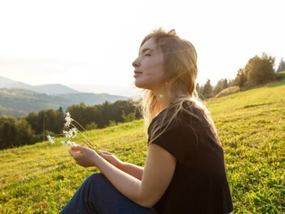 beautiful-blonde-woman-enjoying-mountains-view-holding-camomiles_176420-4166