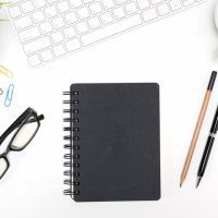 black-notebook-white-desk-table-background-with-copy-space_1357-126