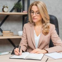 blonde-young-businesswoman-writing-diary-with-pen-office_23-2148029077