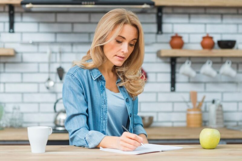 blonde-young-woman-writing-with-pen-notebook-wooden-table_23-2148029224