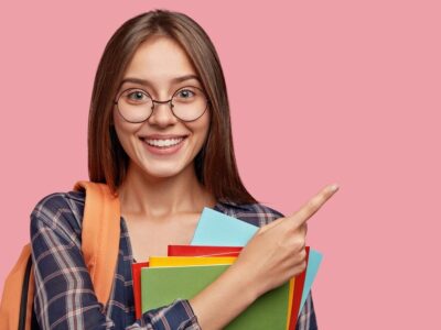 cheerful-student-posing-against-pink-wall-with-glasses_273609-20876