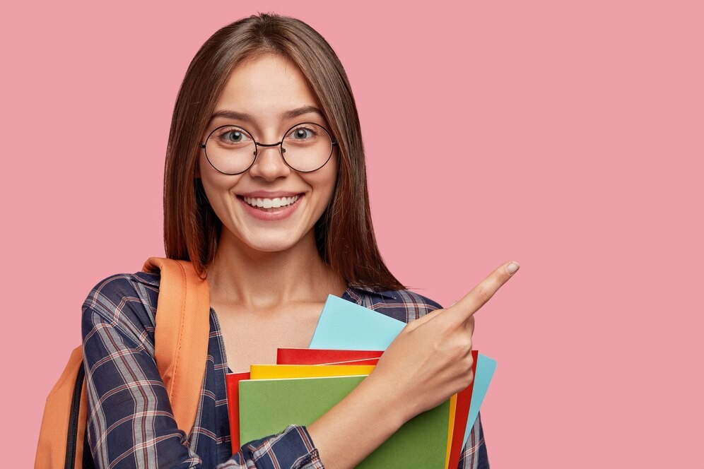 cheerful-student-posing-against-pink-wall-with-glasses_273609-20876