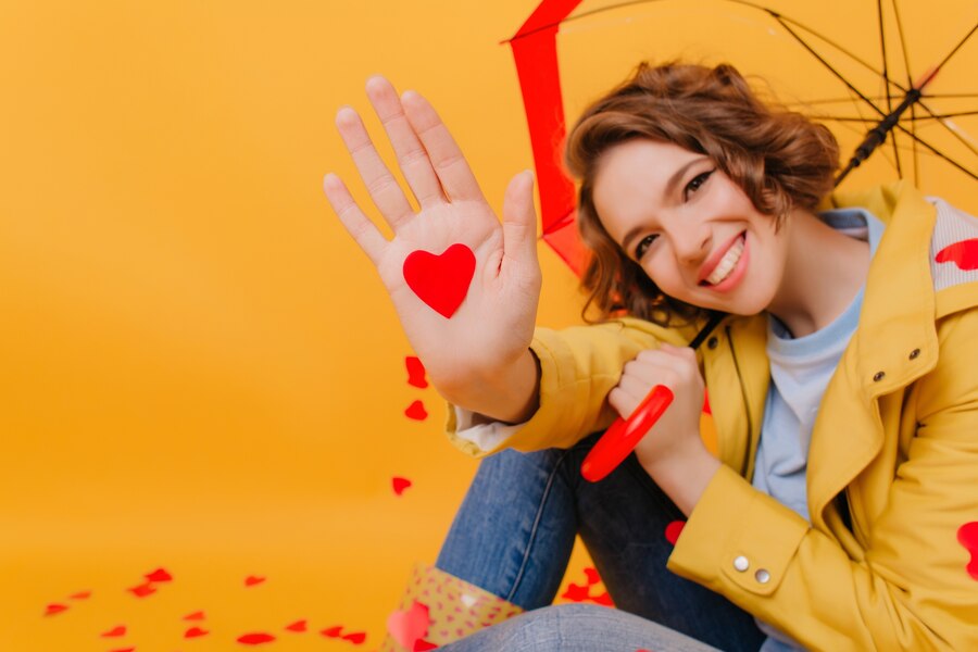 close up portrait laughing lady holding umbrella paper red heart studio shot brunette pale girl smiling photoshoot valentine s day Straipsniai.lt