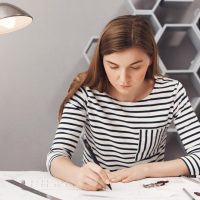 close-up-portrait-young-serious-architect-girl-doing-her-work-cosy-coworking-space-looking-paper-with-serious-unhappy-expression_176420-8521