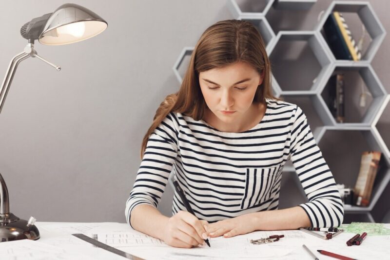 close-up-portrait-young-serious-architect-girl-doing-her-work-cosy-coworking-space-looking-paper-with-serious-unhappy-expression_176420-8521