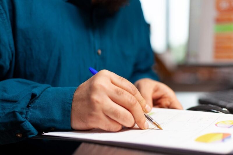 closeup-entrepreneur-hand-sitting-table-analyzing-document-with-company-plan-it-working-management-presentation-writing-business-strategy-businessman-brainstorming-ideas-startup-office_482257-38625