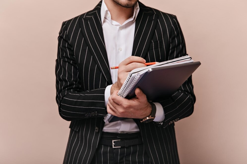 closeup-photo-trendy-man-white-shirt-black-striped-suit-holding-folders-makings-notes-by-pen-posing-isolated-beige-background_197531-29726