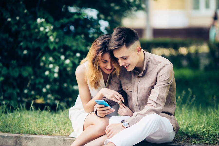 couple sitting using smartphone Straipsniai.lt