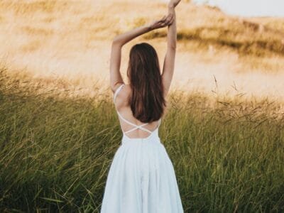 woman wearing white sleeveless dress standing near grass at daytime