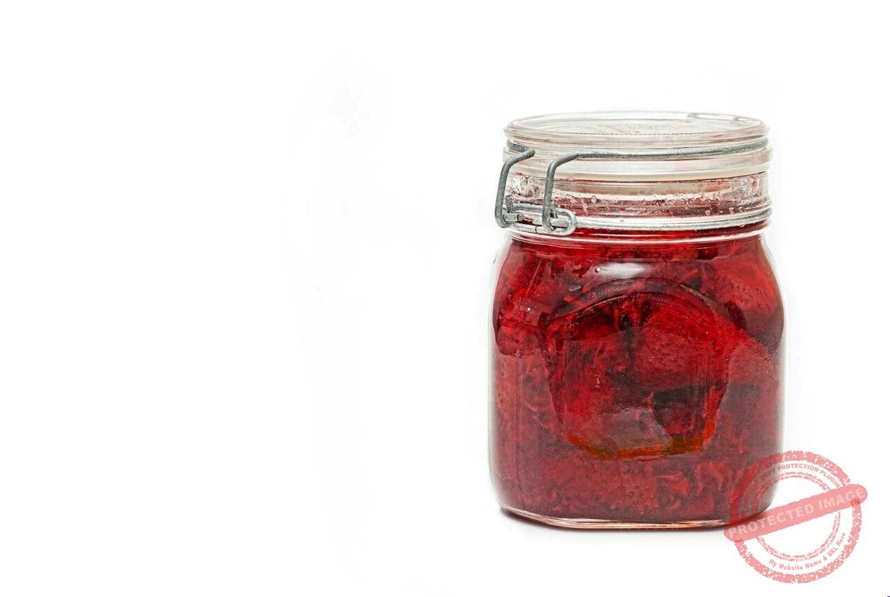 a glass jar filled with red liquid on a white background