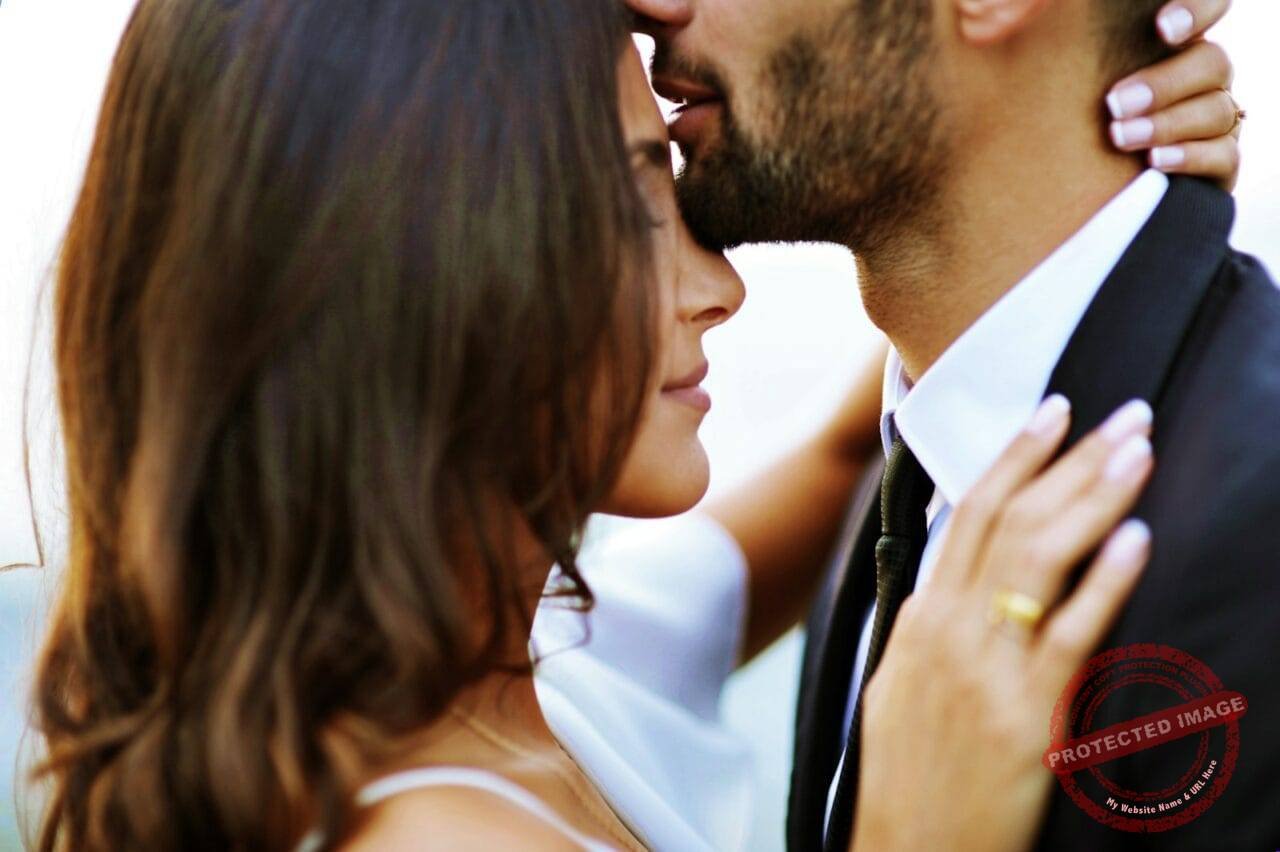 man kissing woman on her forehead
