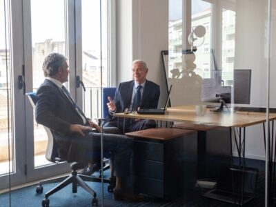 friendly-mature-business-partners-meeting-office-sitting-workplace-with-laptop-talking-view-through-glass-wall-business-portrait-concept_74855-14245