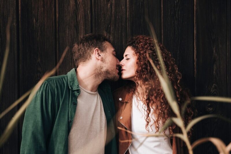 front-view-couple-kissing-with-wooden-background_23-2148243243