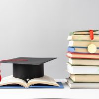 front-view-stacked-books-graduation-cap-open-book-education-day_23-2149241017