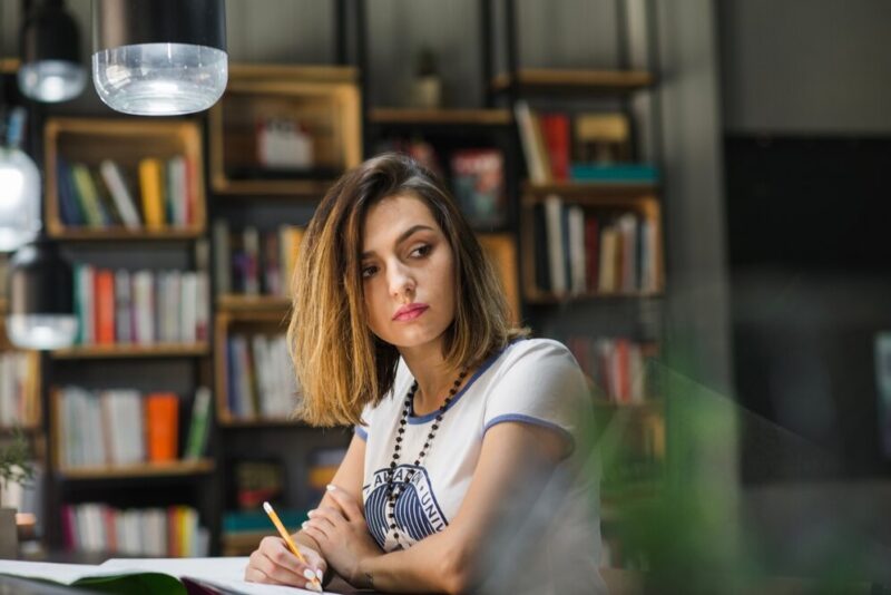 girl-sitting-table-with-notebooks-writing_23-2147657364