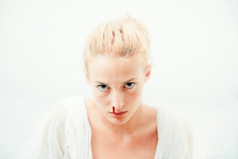 woman's bleeding nose with white background