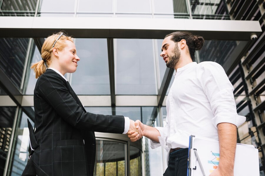 low angle view businessman businesswoman shaking each other hands Straipsniai.lt