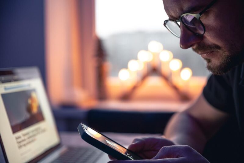 man-with-smartphone-sits-front-laptop-late-night_169016-27154