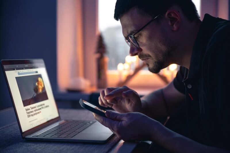 man-with-smartphone-sits-front-laptop-late-night_169016-27294