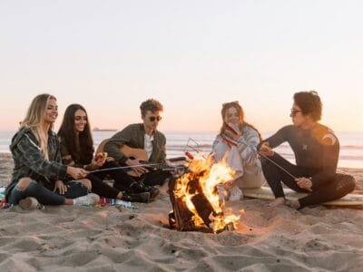 group of people sitting on ground with bonfire during daytime