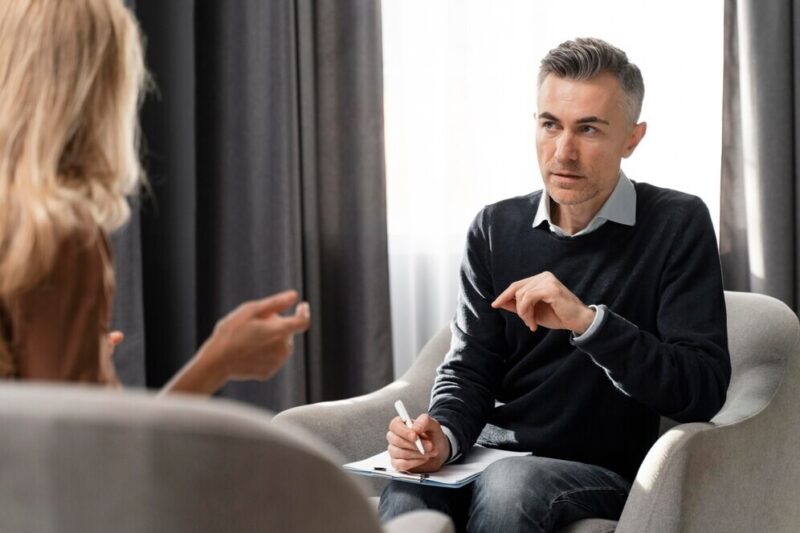 mid-shot-therapist-with-clipboard-looking-patient_23-2148759112