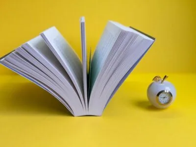 opened-book-yellow-background-with-clock-form-apple-near-it_1268-19880