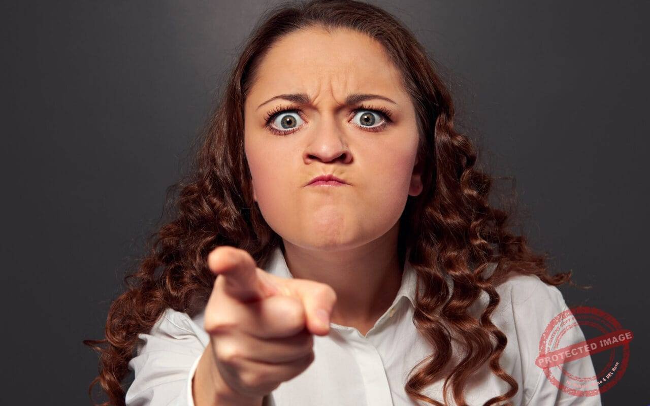 Angry young woman pointing at camera