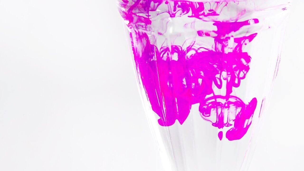 Pink Ink Mixing Transparent Glass Against White Backdrop 23