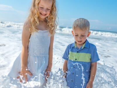 girl in white sleeveless dress standing beside boy in blue and green polo shirt during daytime