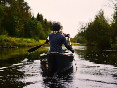 person in blue long-sleeved shirt sitting on kayak while paddling on body of water during daytime