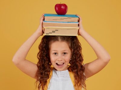 school-girl-holding-books-apple-her-head_23-2148764027