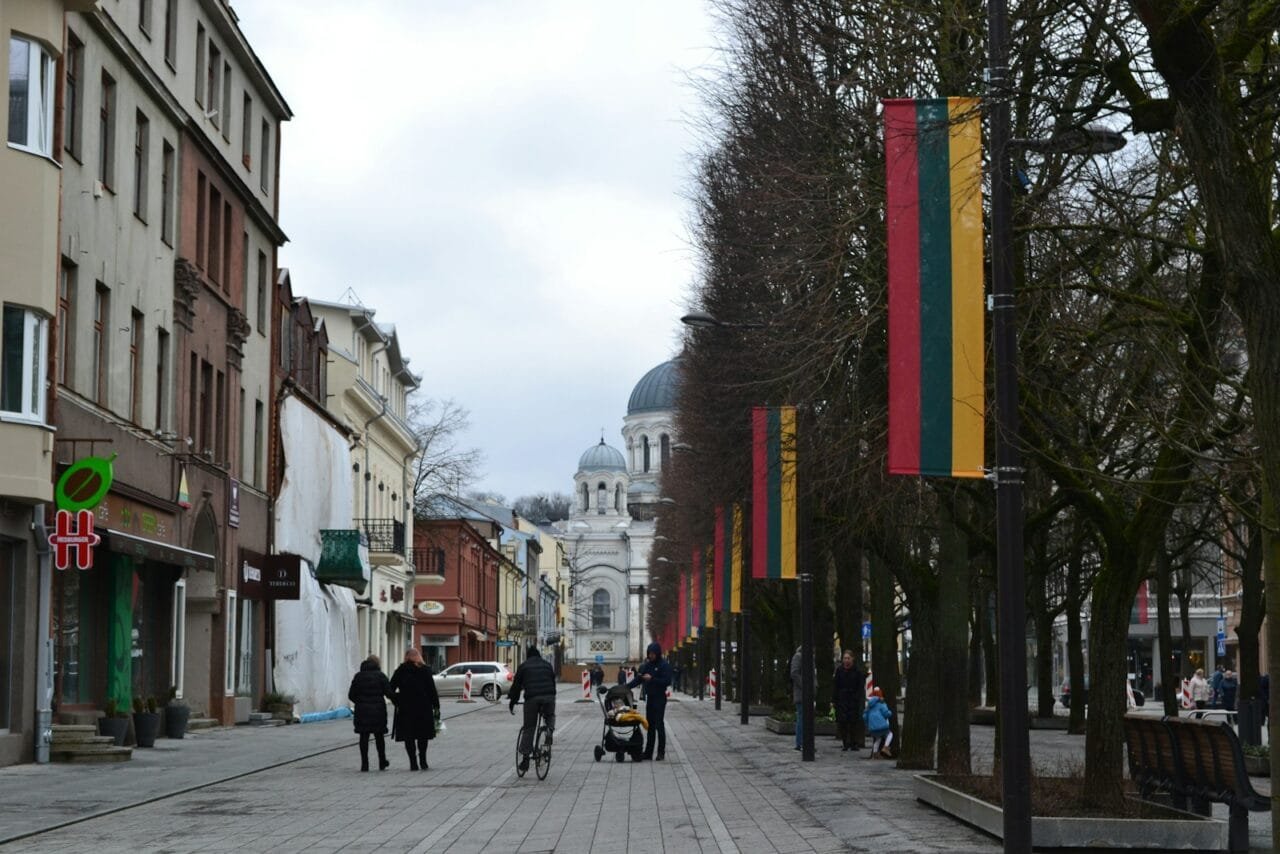 a group of people walking down a street next to tall buildings