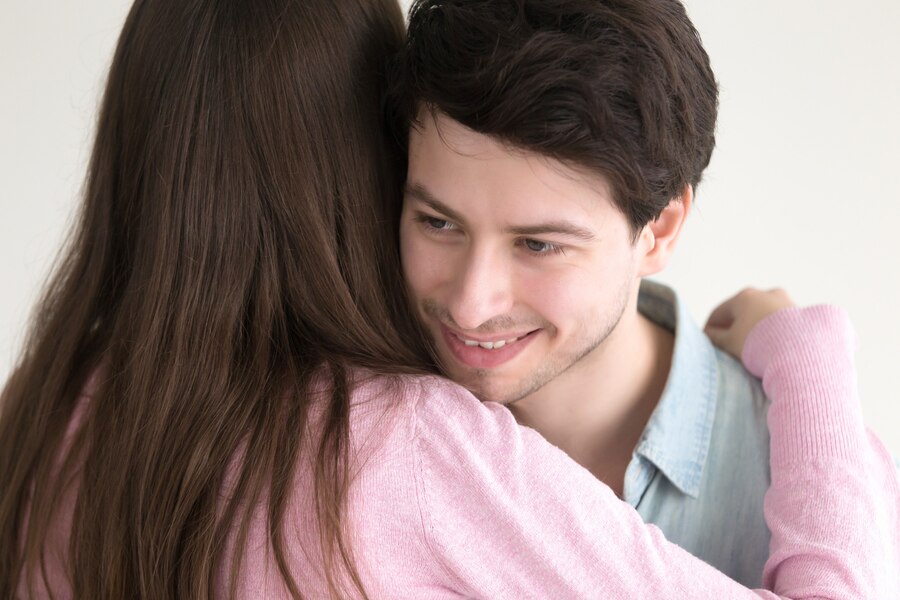 smiling handsome guy embracing young lady Straipsniai.lt