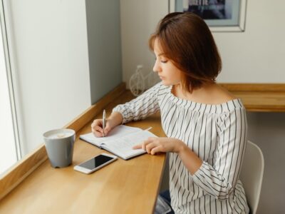 young-business-woman-sitting-cafe-table-use-smartphone-work-with-note-book_8353-5937