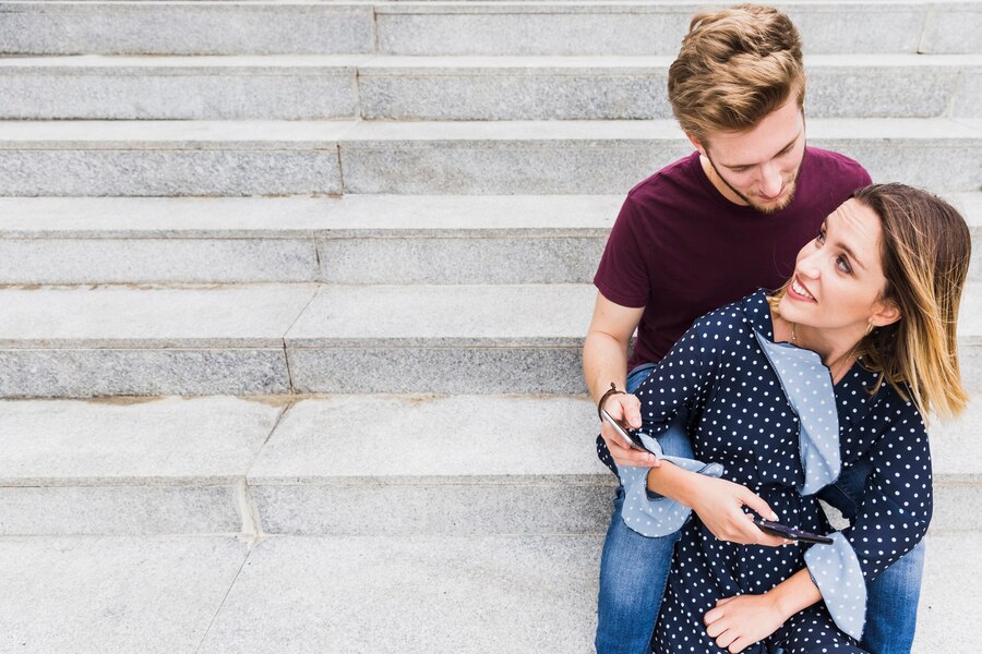 young couple with mobile phone sitting staircase Straipsniai.lt