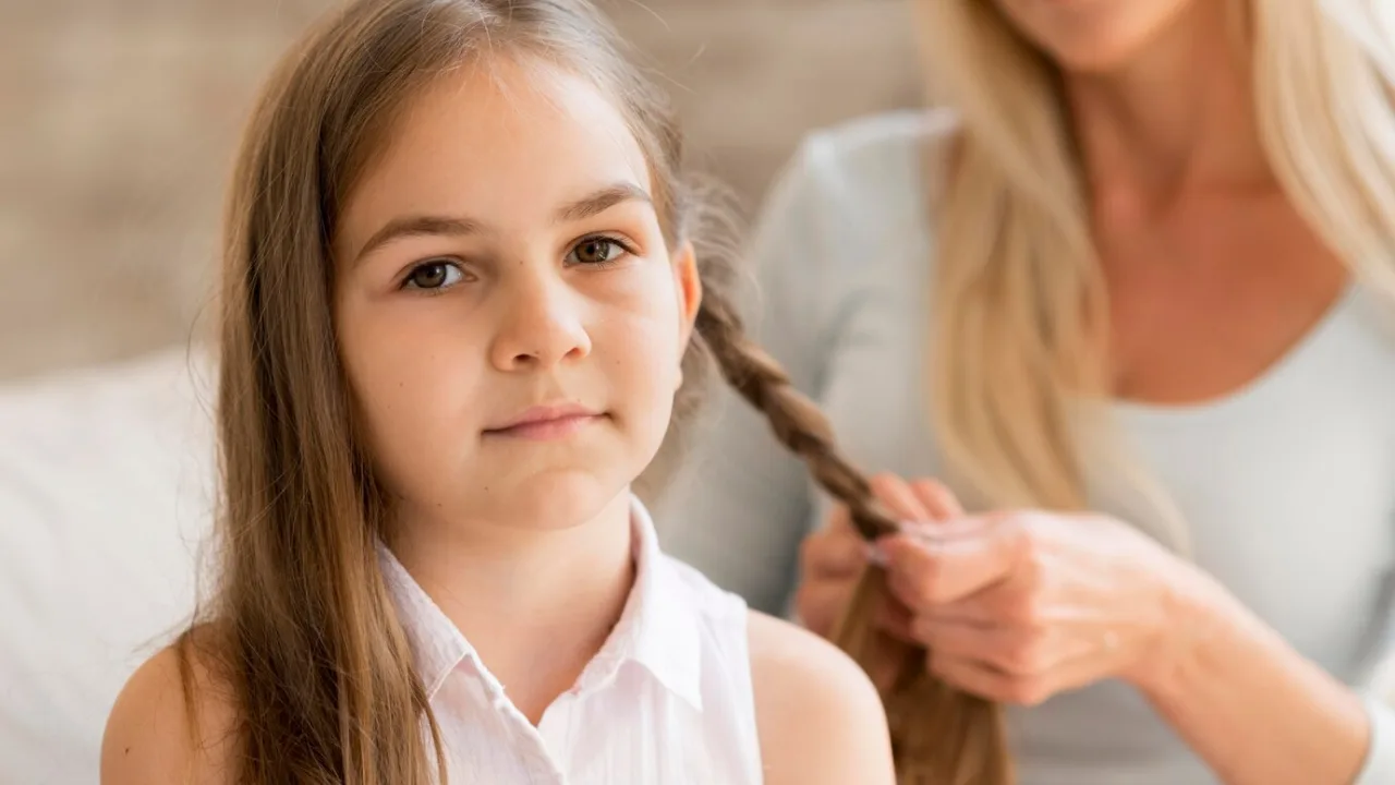 Young girl getting her hair braided by her mother 23 2148602916.jpg