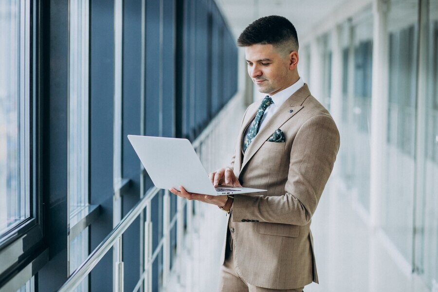 young-handsome-business-man-standing-with-laptop-office