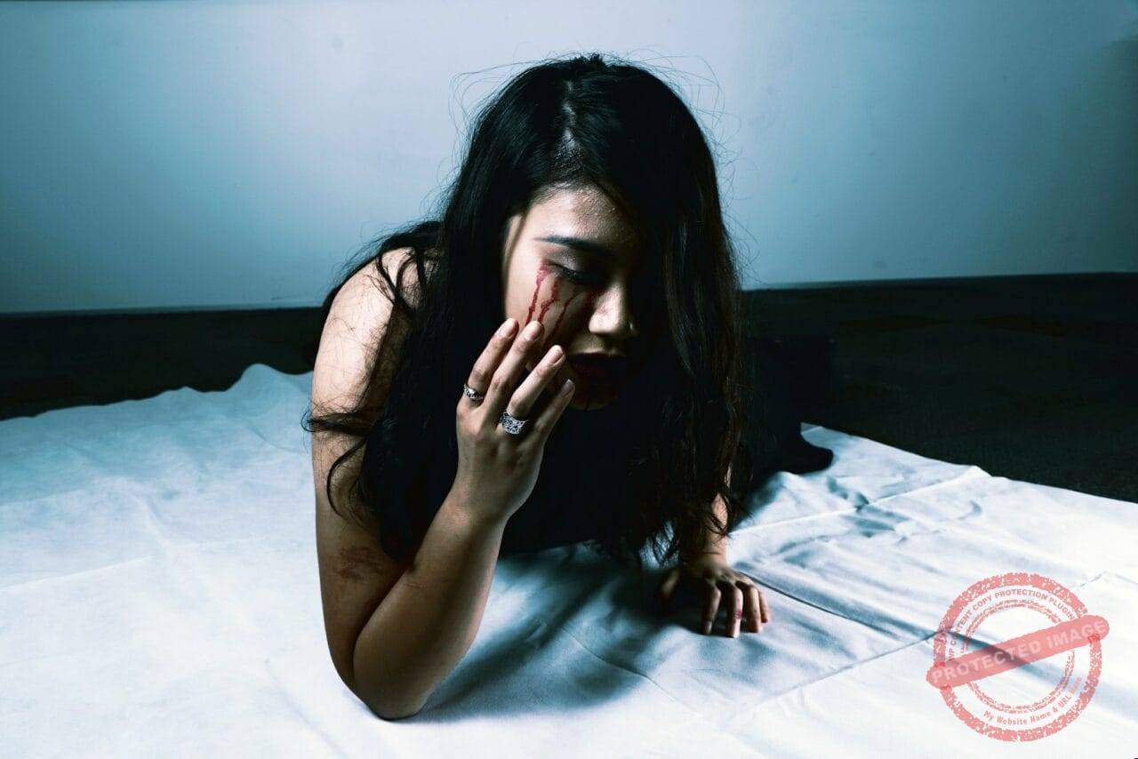 woman crying with red blood prawn lying on bed